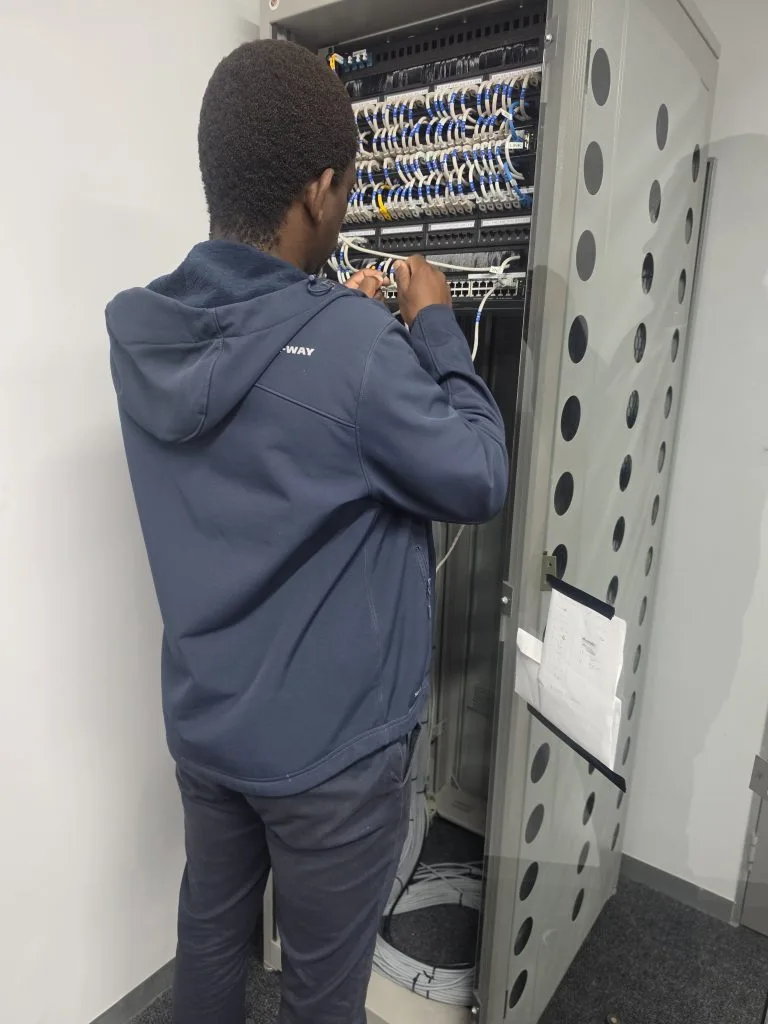 A technician working on connections inside a network cabinet
