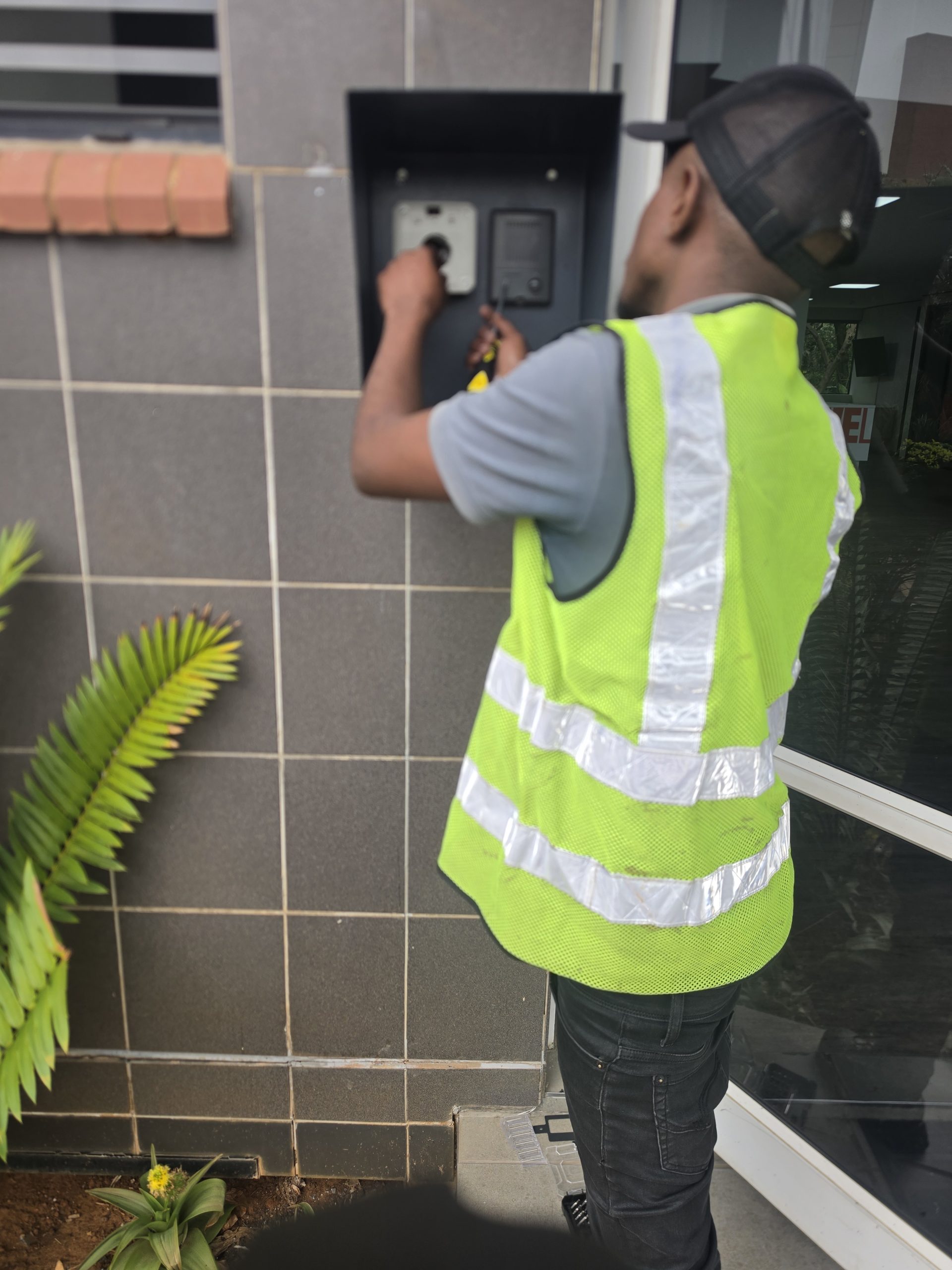 Technician fitting access control equipment at a building entrance