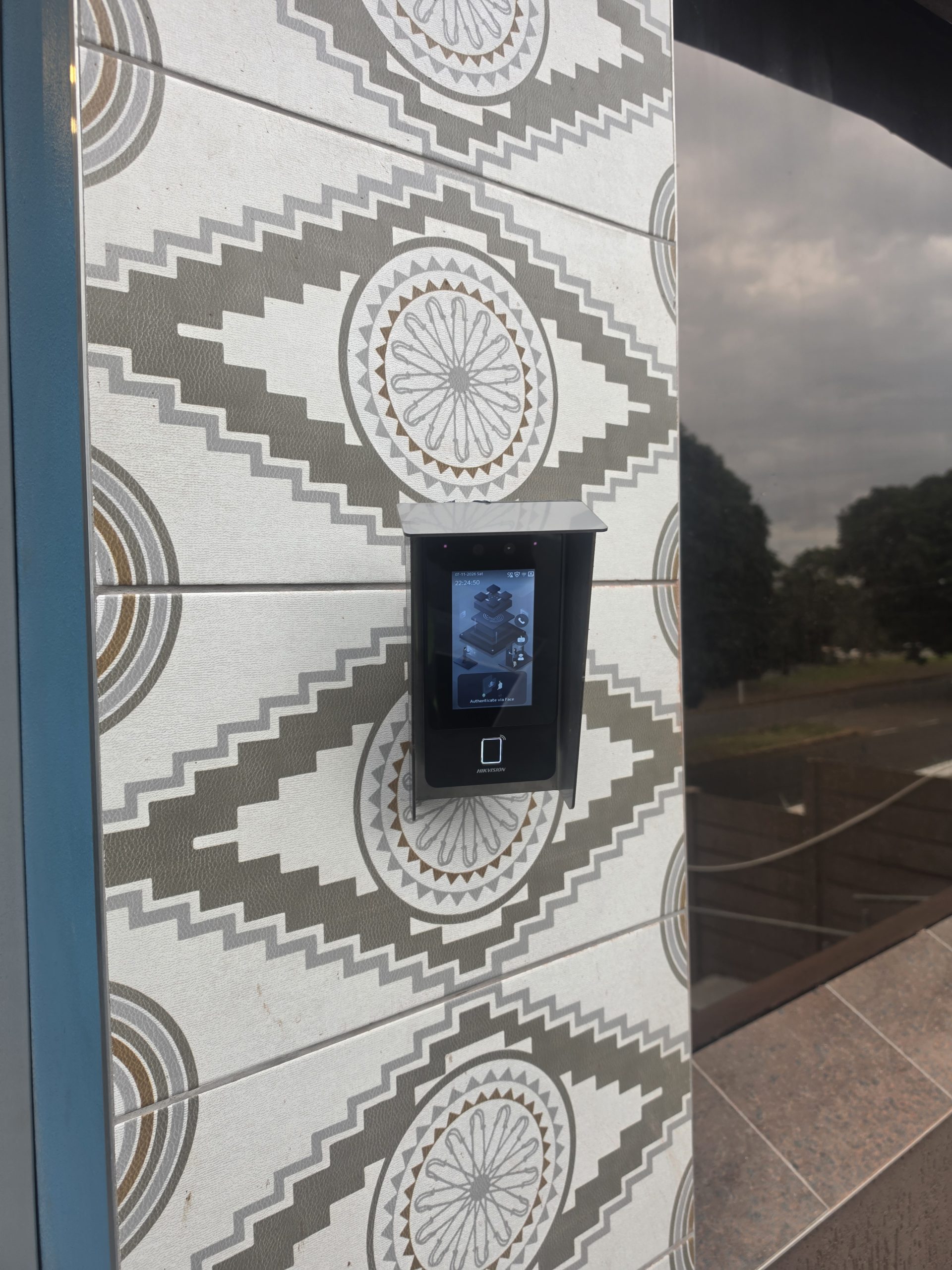 Biometric access reader fitted beside a glass entrance door