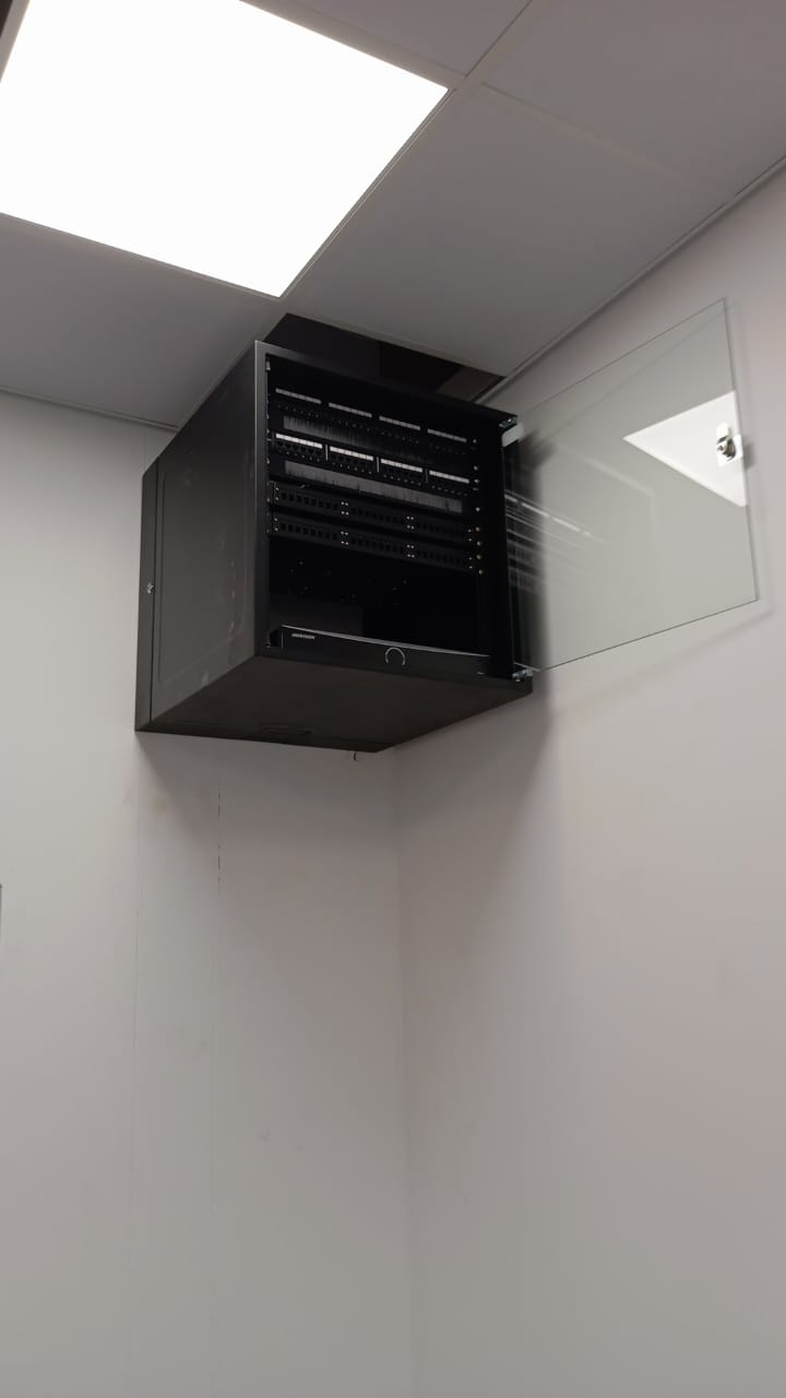 Wall-mounted network cabinet with patch panels and an open glass door