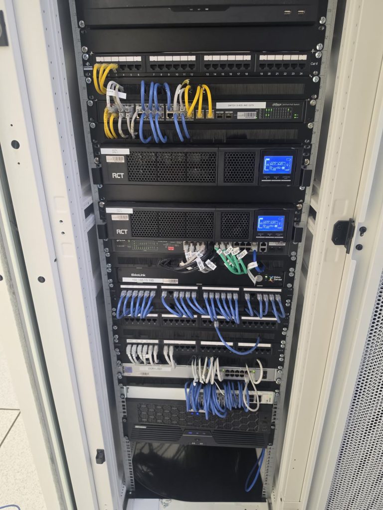 Front of an installed equipment cabinet with patch panels, network switches and UPS units